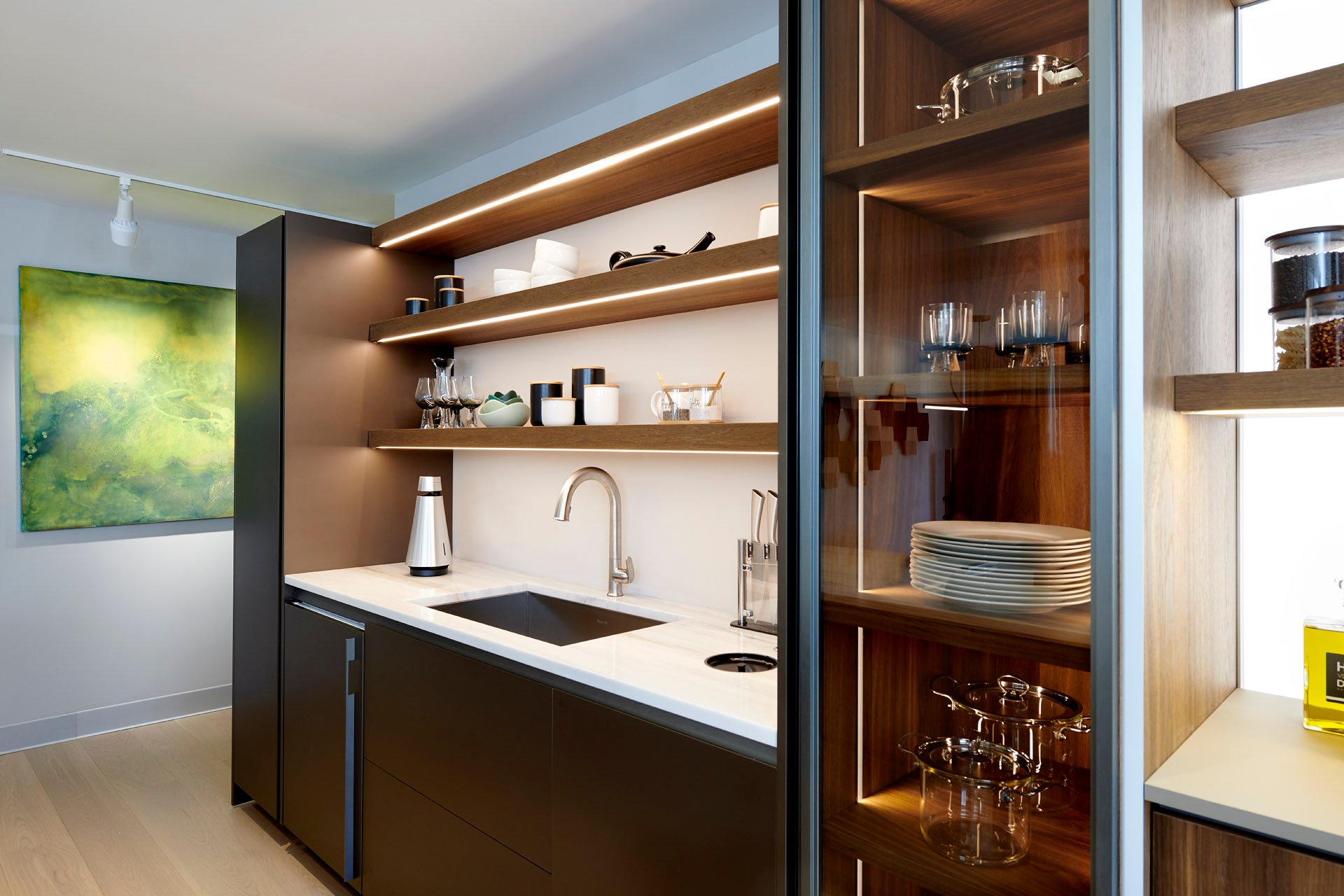 SoWa showroom: a silver speaker on a kitchen counter beside illuminated wood cabinetry